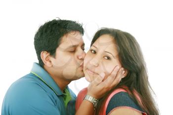 Portrait of woman looking at camera with man near by kissing her 
