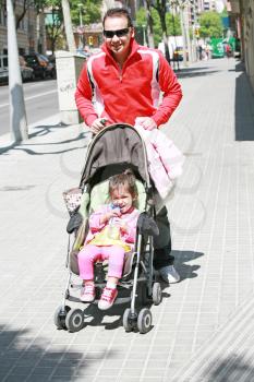 Happy father smiling with his daughter in baby carriage 