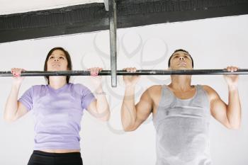 Young adult fitness woman and man preparing to do pull ups in pull up bar.