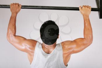 Reaching Goal: Strong man doing pull-ups on a bar in a gym