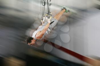 The sportsman the guy, carries out difficult exercise, sports gymnastics, on gym
