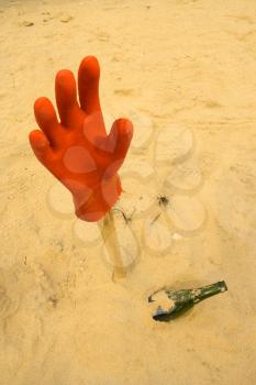 Assistance needed, hanging glove and bottle in the sand