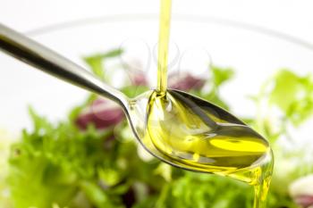 Pouring olive oil in the salad over a spoon