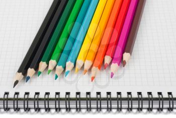 Royalty Free Photo of a Lineup of Multicolored Pencils on a Notebook