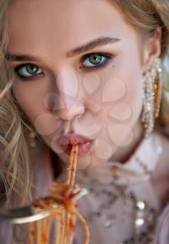 Lovely girl eating pasta (spaghetti). Close-up portrait of a beautiful young woman