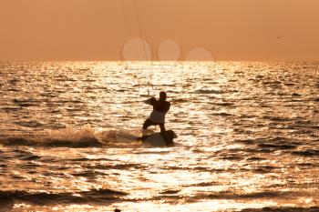 Kite surfer sailing in the sunset sea

