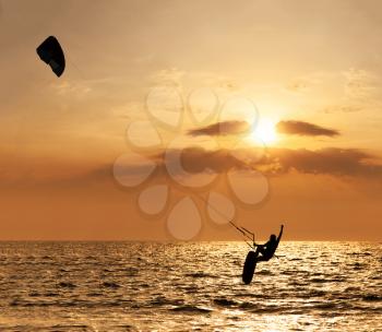 Kite surfer jumping from the water at sunset ocean
