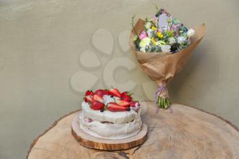 Strawberry cake on wooden table with flowers bouquet
