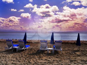 Royalty Free Photo of Deckchairs and Umbrellas on a Beach At Sunset