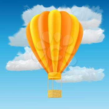 Yellow and orange air ballon with basket fly past clouds