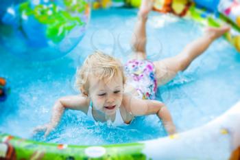 Little blondie girl in the swimming pool, soft focus