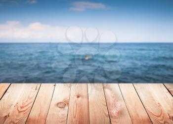 Empty wooden table with blur sea on background.