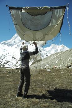 Royalty Free Photo of a Climber Putting Up a Tent in the Himalayan Mountains
