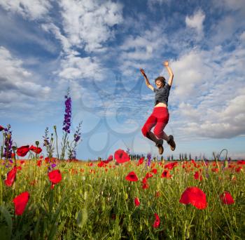 Royalty Free Photo of a Woman Jumping in a Poppy Field