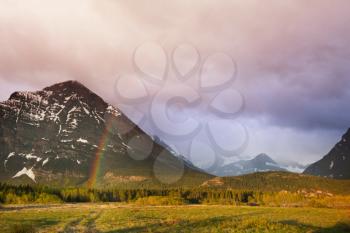 Rainbow above mountains. Beautiful natural landscapes. Picturesque rocky peaks of the Glacier National Park, Montana, USA 