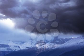 Nature force background - dark stormy sky in snowy mountains