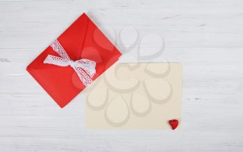 Red envelope and blank paper sheet on white wooden background
