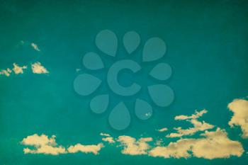 White clouds in blue sky in grunge and retro style.