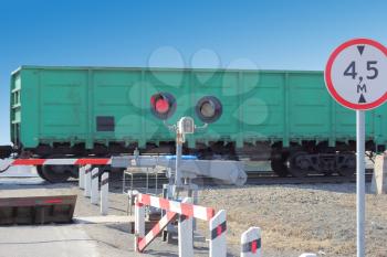 railroad cars at the crossing with a barrier and a red traffic light.