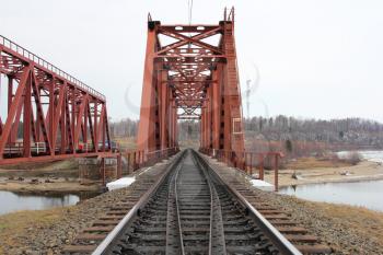 Red metal railway bridge across the river.