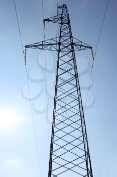 High voltage power pylons against blue sky.