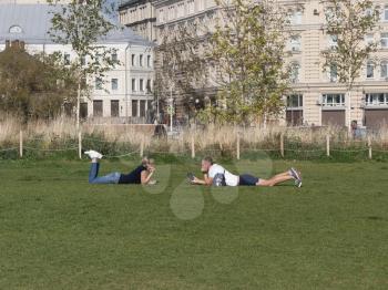 MOSCOW RUSSIA- AUG 25, 2018: Loving couple lying on the grass next to each other looking into the eyes