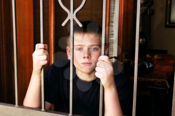 Royalty Free Photo of a Young Boy Locked Behind Security Gate