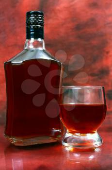 alcohol drink is in a bottle and glass on red background