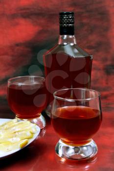lemon alcohol drink is in a bottle and glass on red background