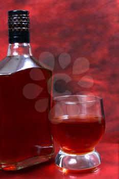 alcohol drink is in a bottle and glass on red background