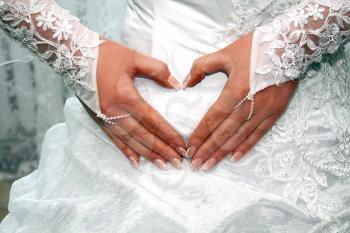 hands of fiancee on a dress as a heart