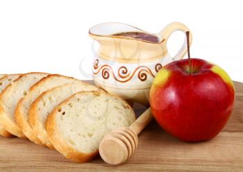 honey in a jug and loaf apple on board isolated on white background