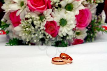two wedding rings and bouquet isolated on white background