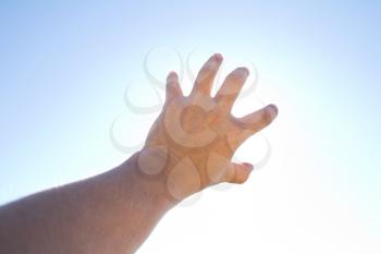 man's hand against the blue sky
