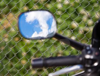 Reflection of clouds on a blue sky in a motobike mirror .