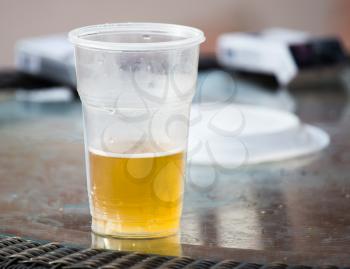 Beer in a plastic glass on the table .