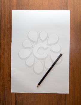 white sheet of paper with a pencil on a wooden background