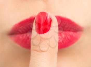 Close-up shot of sexy woman lips with red lipstick and red manicure