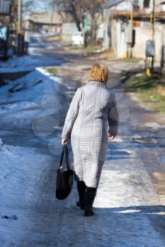a woman with a bag goes on the road in winter
