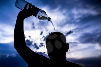 man pours water on his head in the sunset