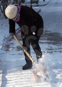 working woman cleans snow shovel in the nature