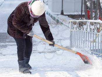 working woman cleans snow shovel in the nature .