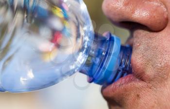 Man drinks water from a plastic bottle .