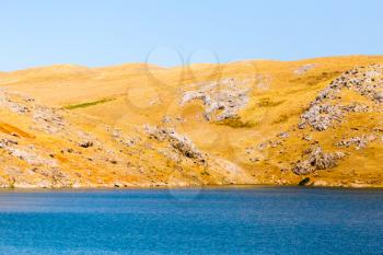 Blue lake near yellow rocks in nature .