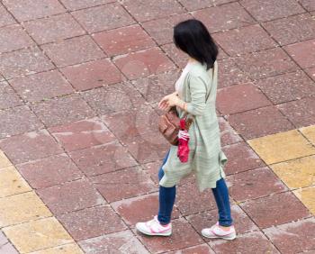 The girl is walking along paving stones .