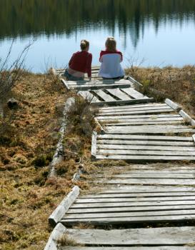 Royalty Free Photo of Two Girls Sitting on a Wooden Pier