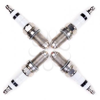Set of four spark plugs arranged in a cross on a white background