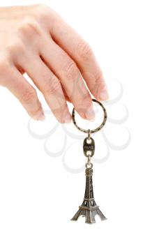 Hand holding small Eiffel Tower statuette on a white background