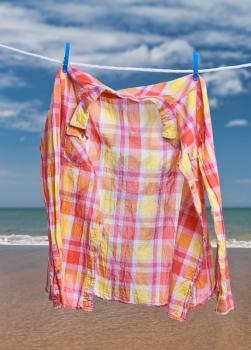 Orange checkered shirt drying on a rope on a tropical beach