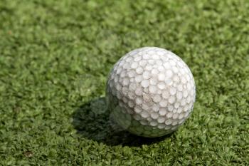 old scratched dirty golf ball on artificial turf